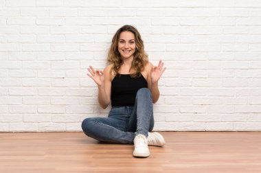 Genç sarışın kadın parmakları ile ok işareti gösteren katta oturan