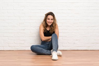 Genç sarışın kadın gülerek katta oturuyor