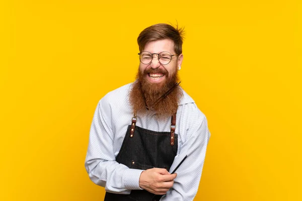 Barber s dlouhými vousy v zástěře nad izolovaným žlutým pozadím — Stock fotografie