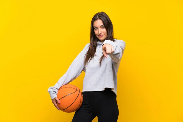 Mladá Žena Hraje Basketbal Přes Izolované Žluté Pozadí Ukazuje Prstem — Stock fotografie