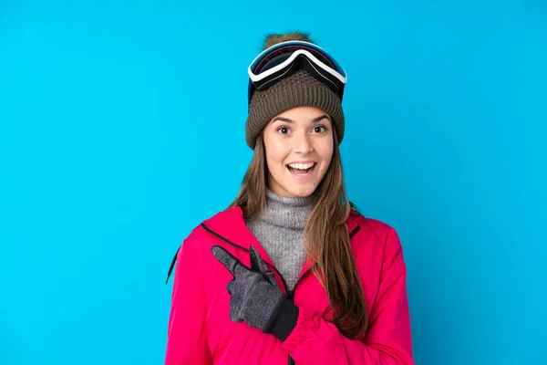 Teenager Skifahrerin Mit Snowboardbrille Über Isoliertem Blauem Hintergrund Zeigt Mit — Stockfoto