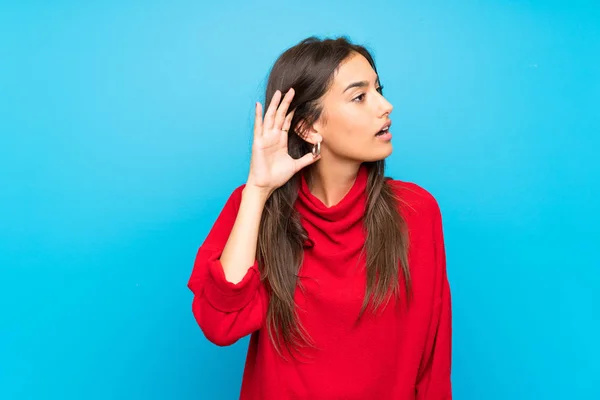 Giovane Donna Con Maglione Rosso Sfondo Blu Isolato Ascoltando Qualcosa — Foto Stock