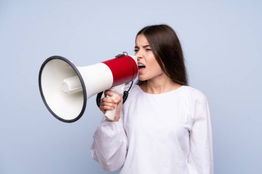 Izole mavi arka plan üzerinde genç kadın bir megafon ile bağırıyor