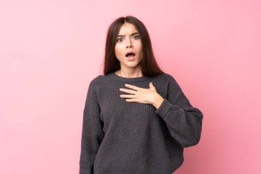 Soyutlanmış pembe arka planı olan genç bir kadın sağa bakarken şaşırmış ve şok olmuştu.