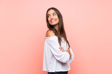 Kolları bağlı ve mutlu bir şekilde pembe arka planda yaşayan genç bir kadın.