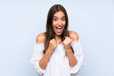 Genç bir kadın mavi arka planda zaferi kutluyor.