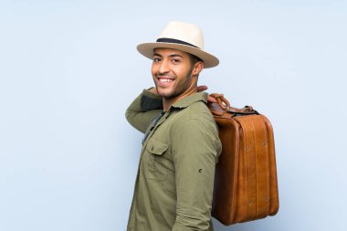 Genç yakışıklı adam izole mavi arka plan üzerinde bir vintage evrak çantası tutan