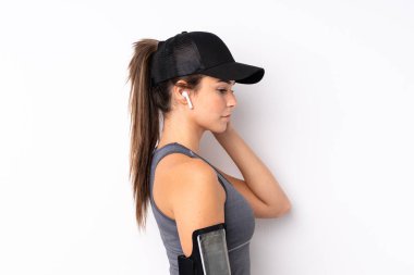 Genç Brezilyalı spor kızı izole edilmiş beyaz arka planda müzik dinliyor.