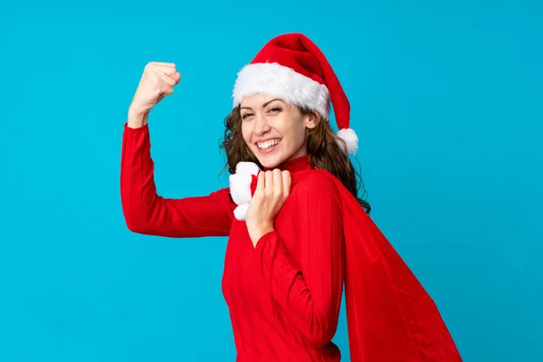 Chica con sombrero de Navidad sosteniendo una bolsa de Navidad llena de regalos sobre un fondo aislado —  Fotos de Stock