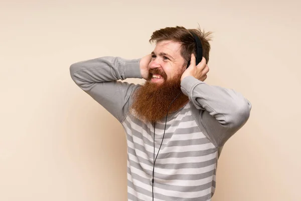 Rudowłosy Mężczyzna Długą Brodą Odizolowanym Tle Pomocą Telefonu Komórkowego Słuchawkami — Zdjęcie stockowe