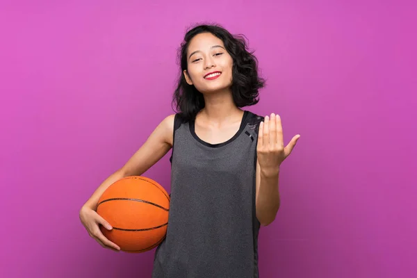 Fiatal ázsiai nő kosárlabdázni át elszigetelt lila háttér — Stock Fotó