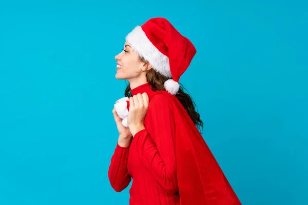 Menina com chapéu de Natal segurando um saco de natal cheio de presentes sobre fundo isolado — Fotografia de Stock