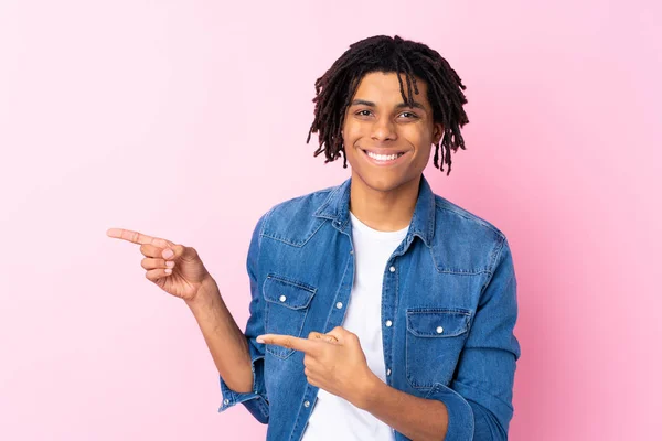 年轻的非洲裔美国人 穿着牛仔衬衫 背对着孤立的粉色背景 手指指向侧面 — 图库照片