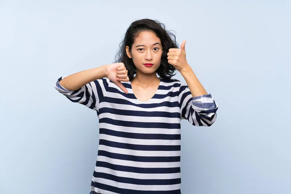Азиатская Молодая Женщина Изолированном Синем Фоне Делает Хороший Плохой Знак — стоковое фото
