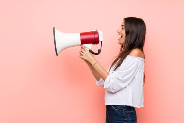 Soyutlanmış pembe arka planda genç bir kadın megafondan bağırıyor.