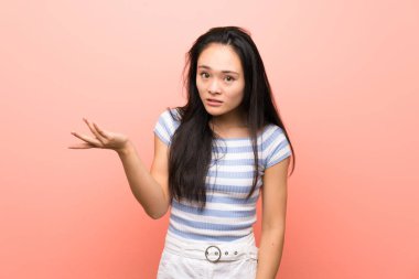 Soyutlanmış pembe arka planda Asyalı genç bir kız şüpheli hareketler yapıyor.