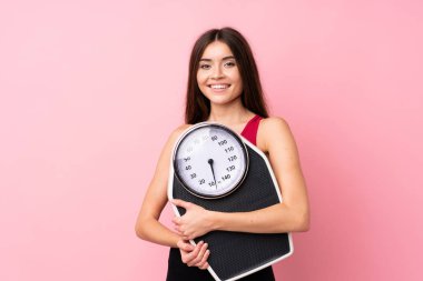 Tartı makinesi ile izole edilmiş pembe arka planda tartı makinesiyle güzel bir genç kız.