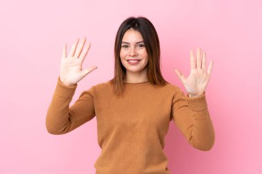Soyutlanmış pembe arka planı olan genç bir kadın parmaklarıyla ona kadar sayıyor.