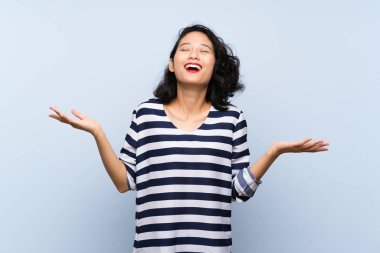 Asyalı genç bir kadın soyutlanmış mavi arka planda gülümsüyor.