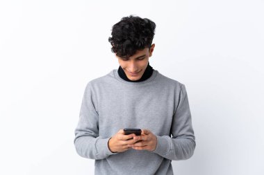 Arjantinli genç bir adam izole edilmiş beyaz arka planda cep telefonuyla mesaj gönderiyor.