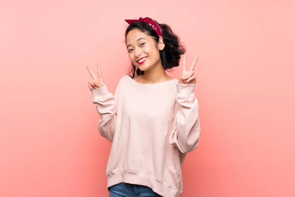 亚洲的年轻女子 身披粉色背景 双手都是胜利的标志 — 图库照片