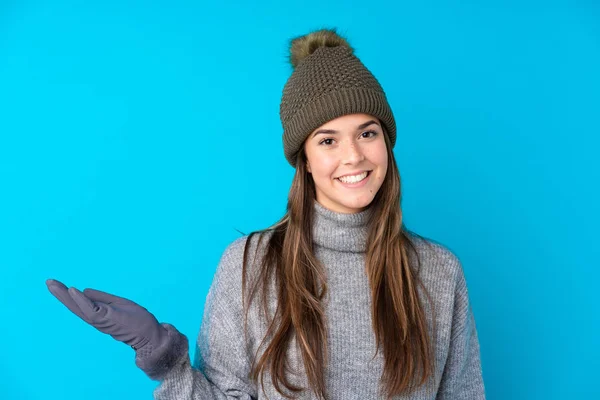 一个戴着冬帽的少女 身披孤零零的蓝色背景 手心拿着想象中的复制空间 — 图库照片