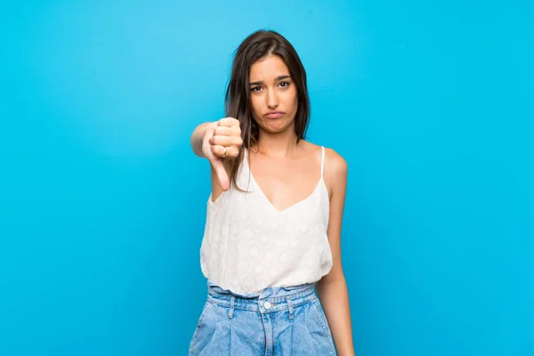 Zole Edilmiş Mavi Arka Planda Genç Bir Kadın Baş Parmağını — Stok fotoğraf