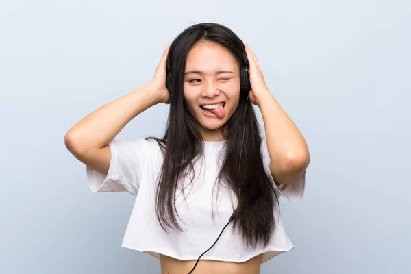 Adolescente asiático chica escuchar música sobre aislado azul pared —  Fotos de Stock