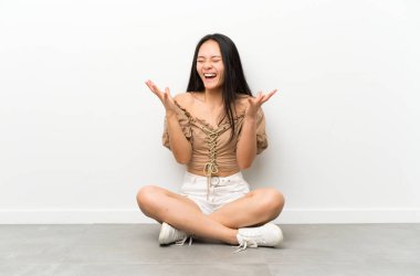 Genç asyalı kız katta mutsuz ve bir şey ile sinirli oturan