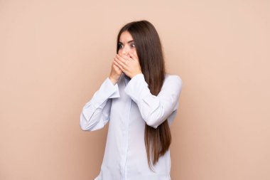 İzole edilmiş arka planı olan genç bir kadın ağzını kapatıp yan tarafa bakıyor.
