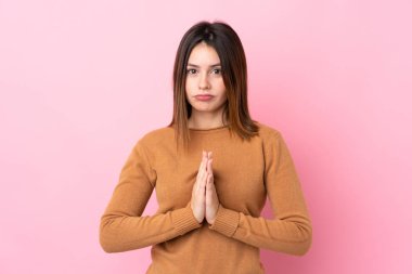 Soyutlanmış pembe arka planı olan genç bir kadın avuç içlerini bir arada tutuyor. İnsan bir şey ister.