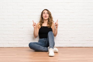 Genç sarışın kadın işaret parmağı ile işaret katta oturan harika bir fikir