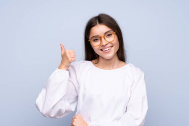 Gözlüklü, soyutlanmış mavi arka planı olan genç bir kadın.