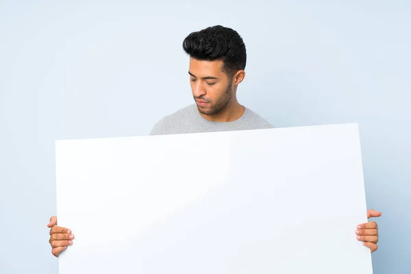 コンセプトを挿入するための空の白いプラカードを保持する孤立した背景の上の若いハンサムな男 — ストック写真