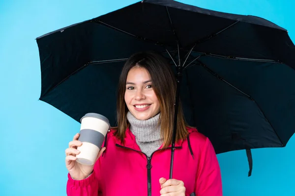 Young woman holding an umbrella and coffee to take away over iso