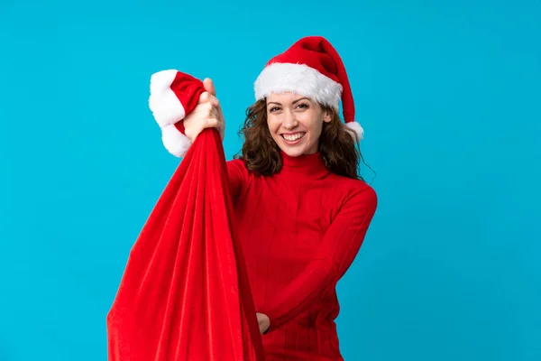 Chica con sombrero de Navidad sosteniendo una bolsa de Navidad llena de regalos sobre un fondo aislado —  Fotos de Stock