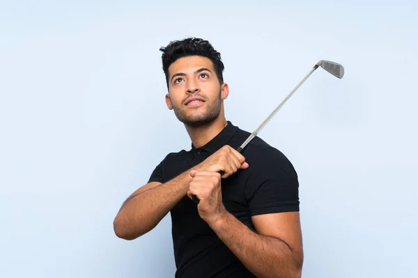 Красивий молодий чоловік грає в гольф над ізольованим синім тлом — стокове фото