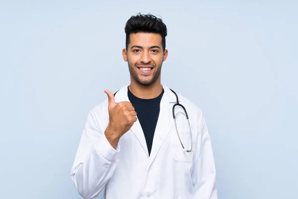 Joven Doctor Sobre Aislado Muro Azul Con Pulgares Arriba Porque — Foto de Stock