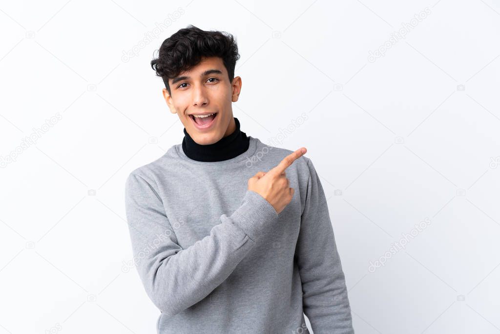 Young Argentinian man over isolated white background surprised and pointing side