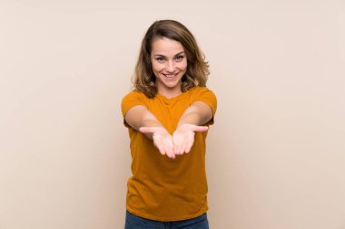 Bir reklam eklemek için avuç üzerinde copyspace hayali tutan izole arka plan üzerinde Genç sarışın kız