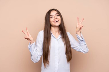 Tecrit edilmiş genç bir kadın zafer işaretini iki eliyle gösteriyor.