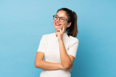 Genç esmer kız gözlüklü, soyutlanmış mavi arka plan.