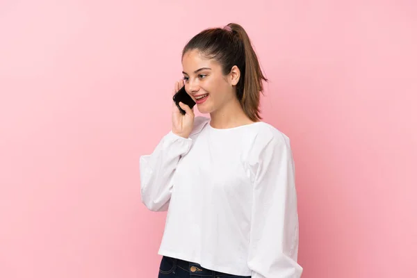 Stock image Young brunette girl over isolated pink background keeping a conversation with the mobile phone