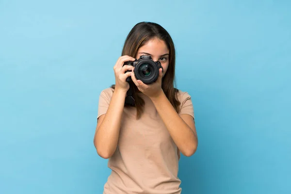 Chica Morena Joven Sobre Fondo Azul Aislado Con Una Cámara — Foto de Stock