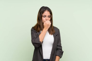 İzole edilmiş yeşil arka planda ceketi olan esmer bir kız. Şüpheleri var.