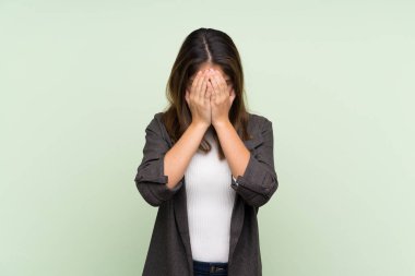 Spor ceketli genç esmer kız izole edilmiş yeşil arka plan, yorgun ve hasta bir yüz ifadesi var.