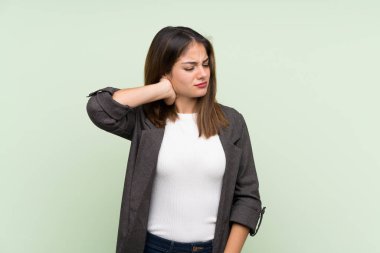 Siyah ceketli genç esmer kız izole edilmiş yeşil arka planı ve boyun ağrısı var.
