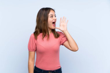 Genç esmer kız mavi arka planda, ağzı açık bağırıyor.