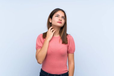 Genç esmer kız izole edilmiş mavi arka planda bir fikir düşünüyor.