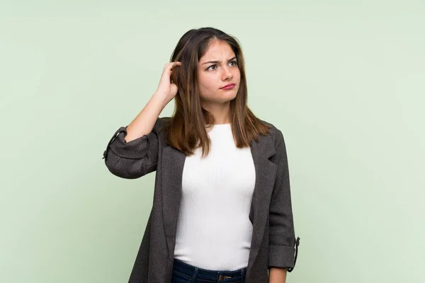 Young Brunette Girl Blazer Isolated Green Background Having Doubts — Stock Photo, Image